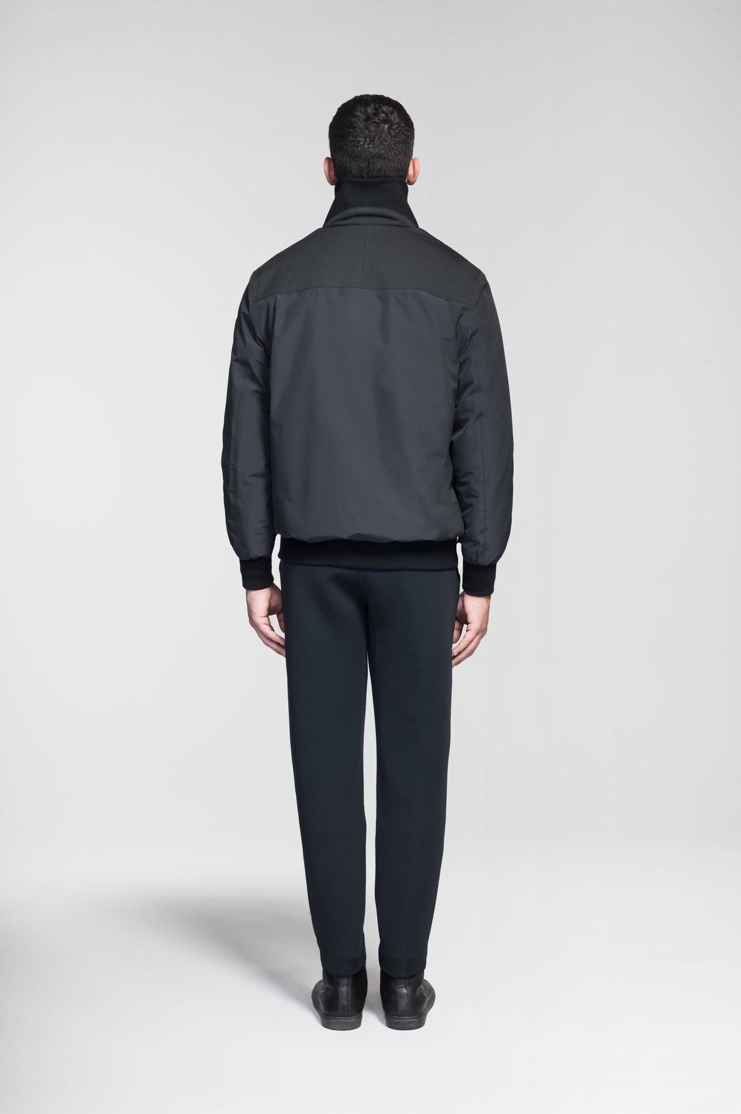 Flint Men's Tailored Rib Collar Jacket in hip length, premium 3-ply Micro Denier fabrication, premium 4-way stretch, water resistant Primaloft Gold Insulation Active +, flap pockets with magnetic closure at waist, side entry pockets at waist, ribbed sleeve cuffs, two-way branded zipper at centre front, box pleat detailing at centre back, large interior zipper pocket, and interior button pocket at left chest, in Black