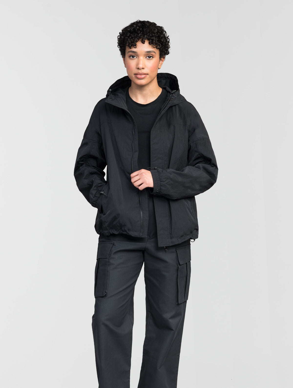 Hartley Women's Tailored Rain Jacket in hip length, two-way centre front zipper with wind flap, toggle adjustable cuffs and waist cord, non-removable hood, side entry waist pockets, in Black