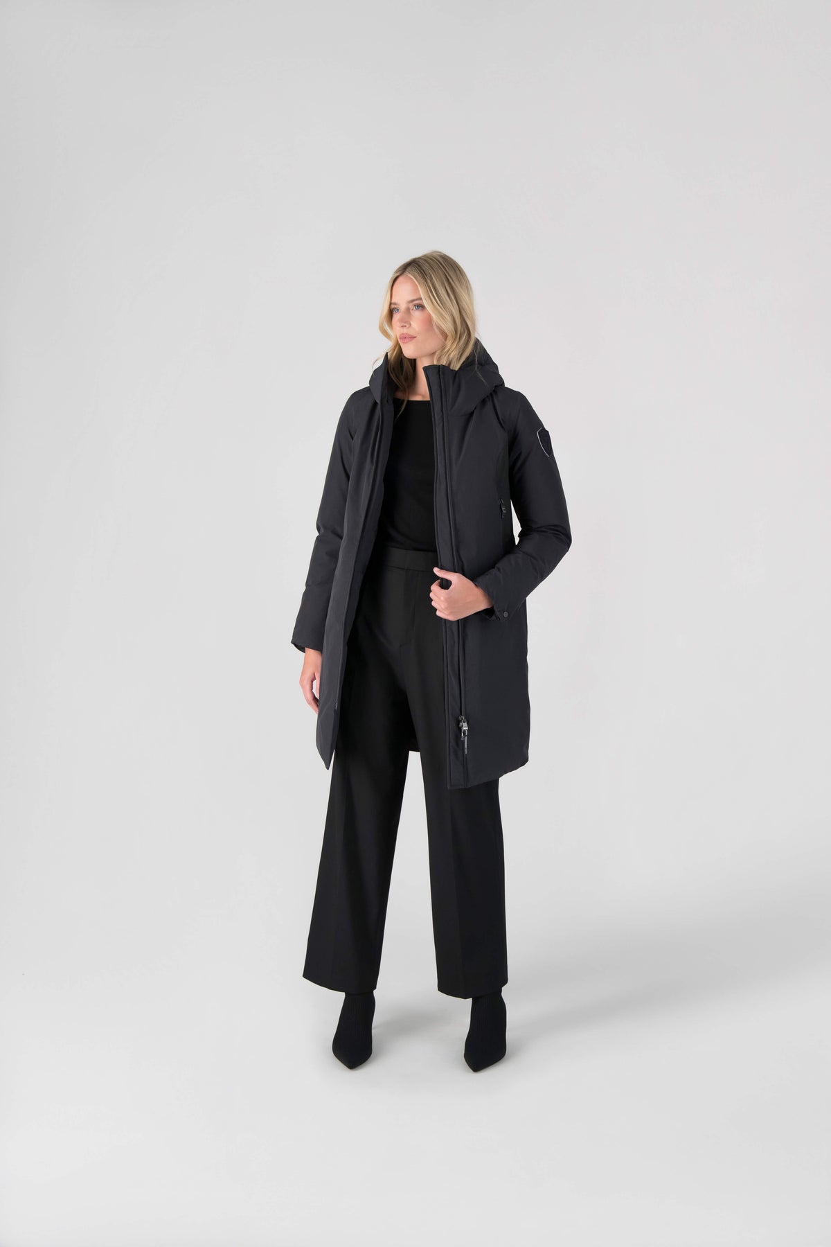 Inara Women's Performance Parka in knee length, premium 3-ply micro denier and stretch ripstop fabrication with DWR coating, Premium Canadian White Duck Down insulation, non-removable down-filled hood, centre front two-way zipper, large vertical zipper pockets along waist, zipper vents along bottom side hem, in Black