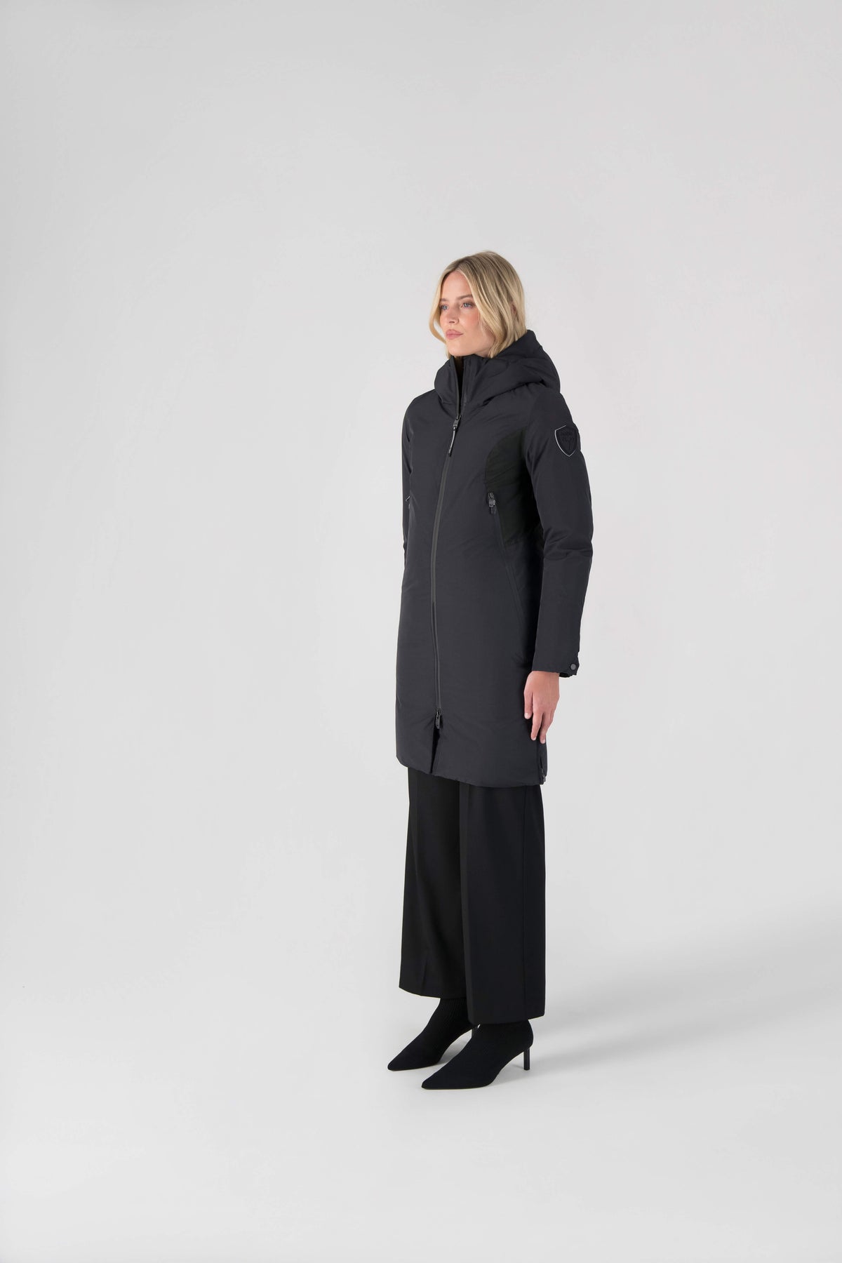 Inara Women's Performance Parka in knee length, premium 3-ply micro denier and stretch ripstop fabrication with DWR coating, Premium Canadian White Duck Down insulation, non-removable down-filled hood, centre front two-way zipper, large vertical zipper pockets along waist, zipper vents along bottom side hem, in Black