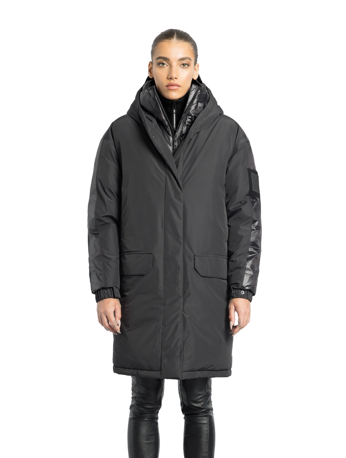 Slyn Women's Performance Parka in thigh length, premium 3-ply micro denier and cire technical nylon taffeta fabrication, Premium Canadian origin White Duck Down insulation, non-removable down-filled hood, inner hooded gilet, two-way centre-front zipper with magnetic closure wind flap, fleece-lined pockets at chest and waist, pit zipper vents, in Black