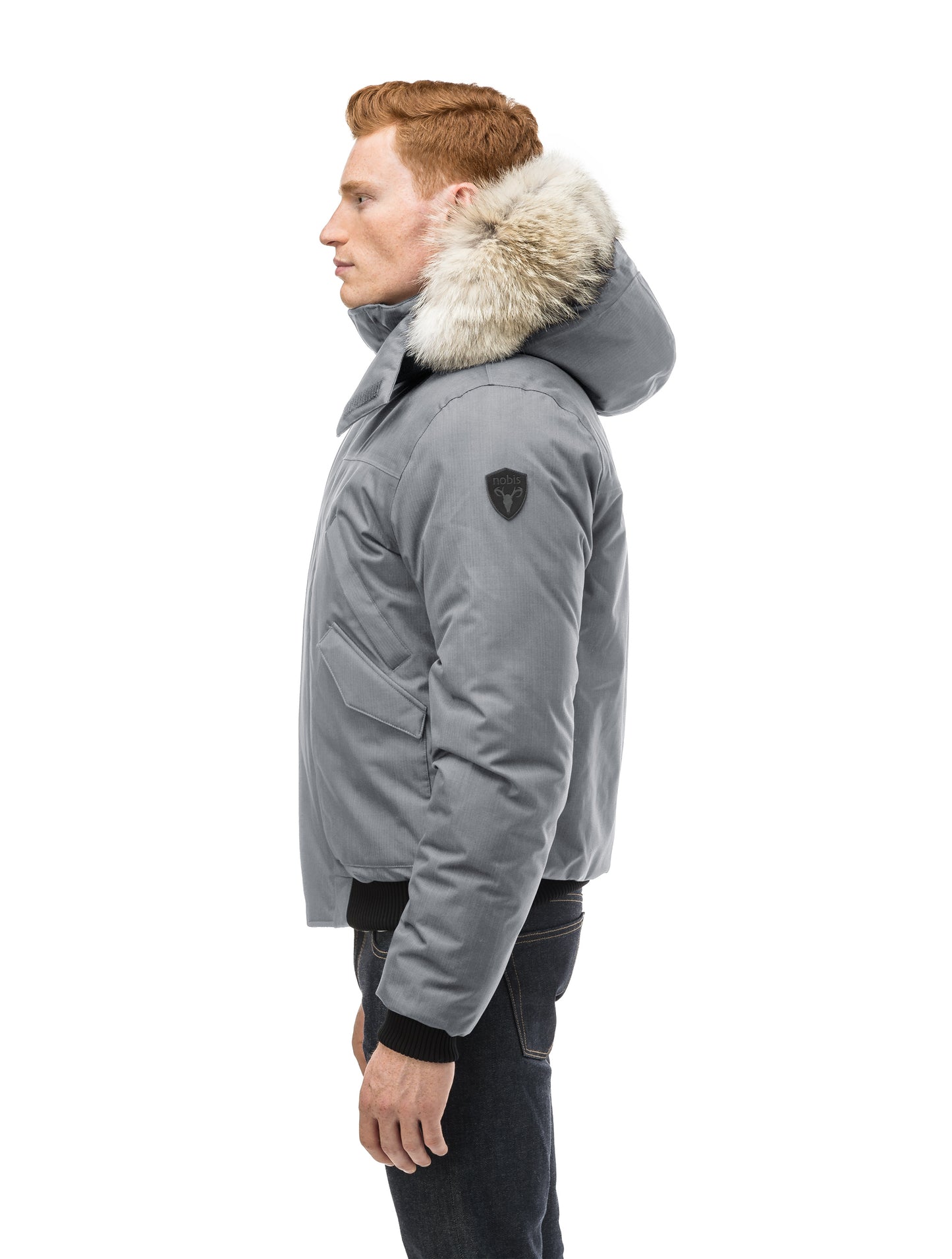 Men's classic down filled bomber jacket with a down filled hood that features a removable coyote fur trim and concealed moldable framing wire in Concrete