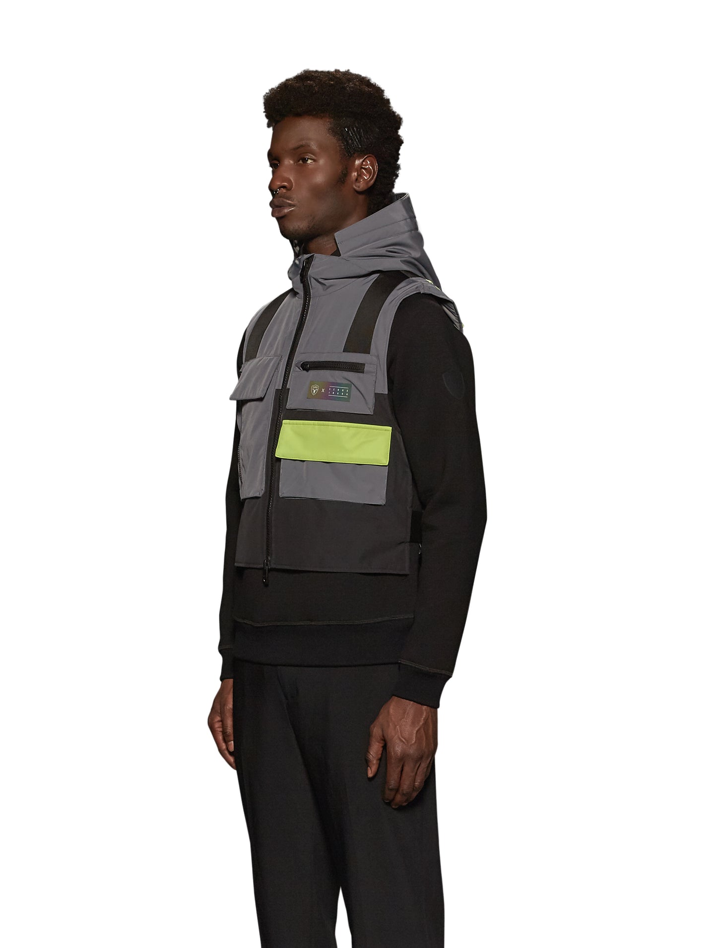 Unisex waist length hooded tactical vest with multiple exterior pockets on front and back, and adjustable side webbing fasteners, colour blocked in Concrete/Black